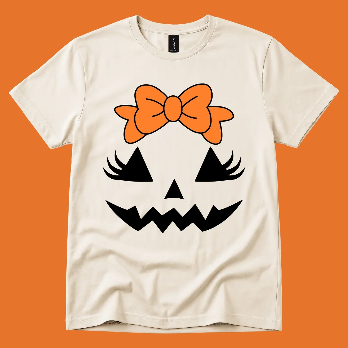 Cute pumpkin face graphic with orange bow, triangle eyes, nose, and jagged smile.