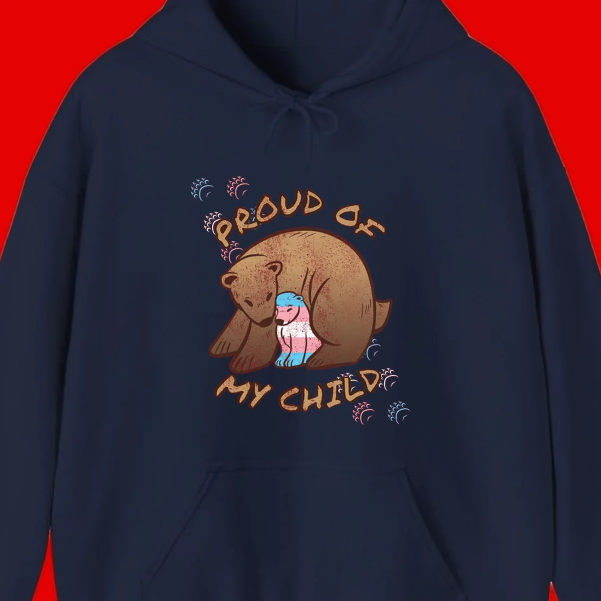 Brown bear holding a cub with blue, pink and white stripes, surrounded by 'Proud As My Chubby' text and decorative wave designs celebrating transgender pride