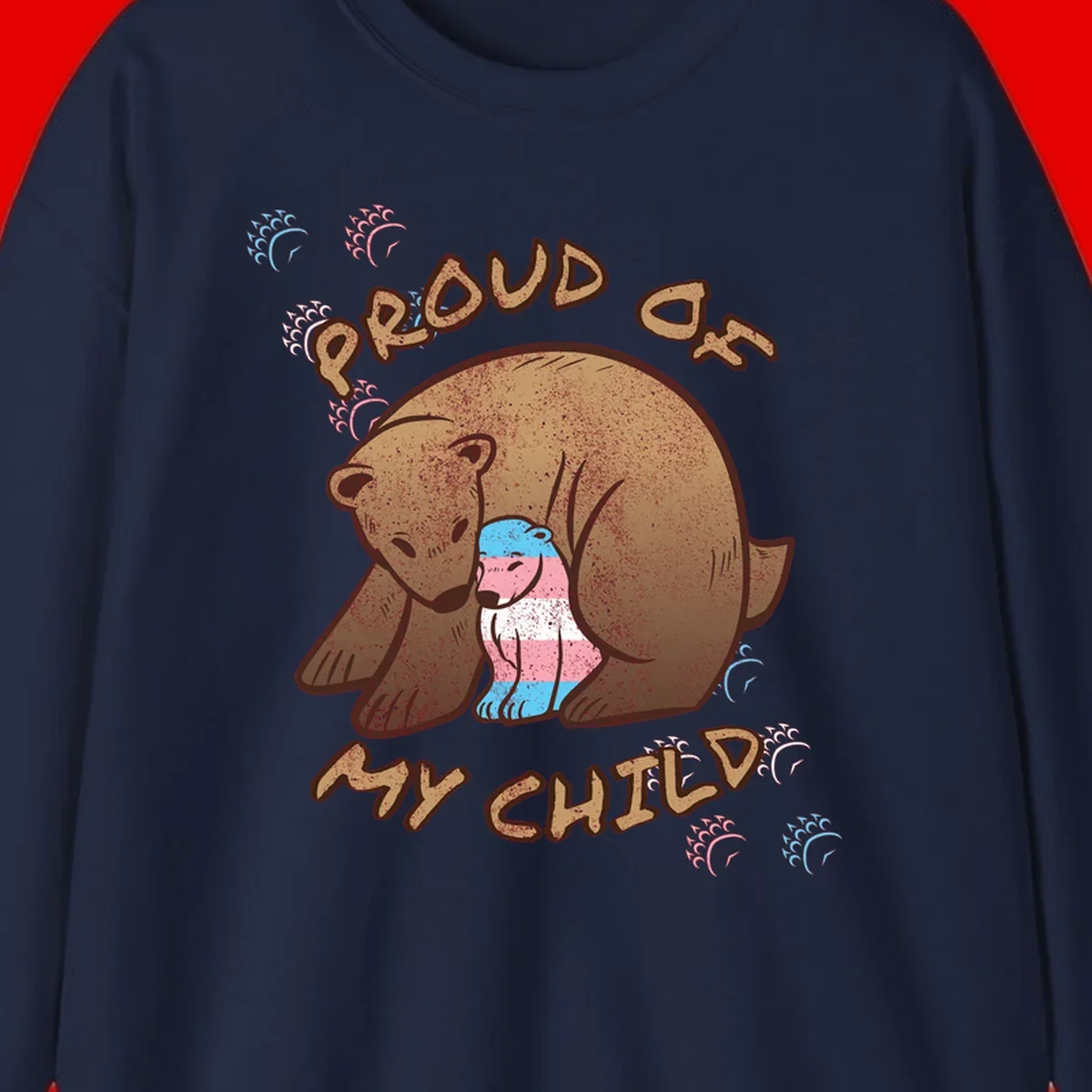 Brown bear holding a cub with blue, pink and white stripes, surrounded by 'Proud As My Chubby' text and decorative wave designs celebrating transgender pride