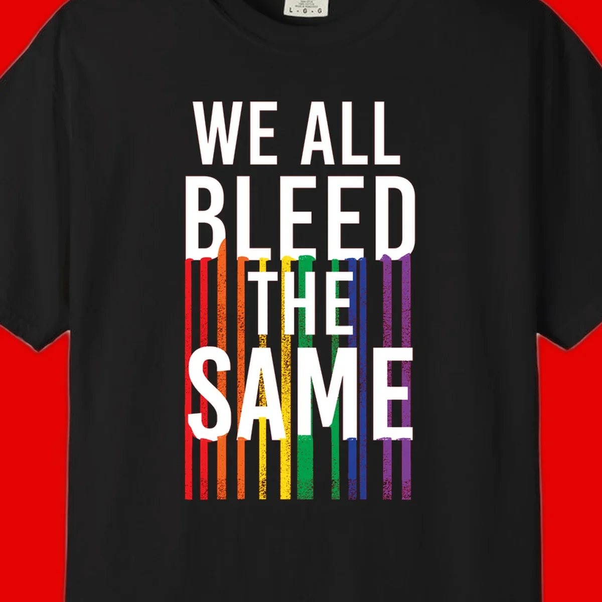 White bold text 'We All Bleed The Same' over rainbow vertical stripes in pride flag colors on gray background