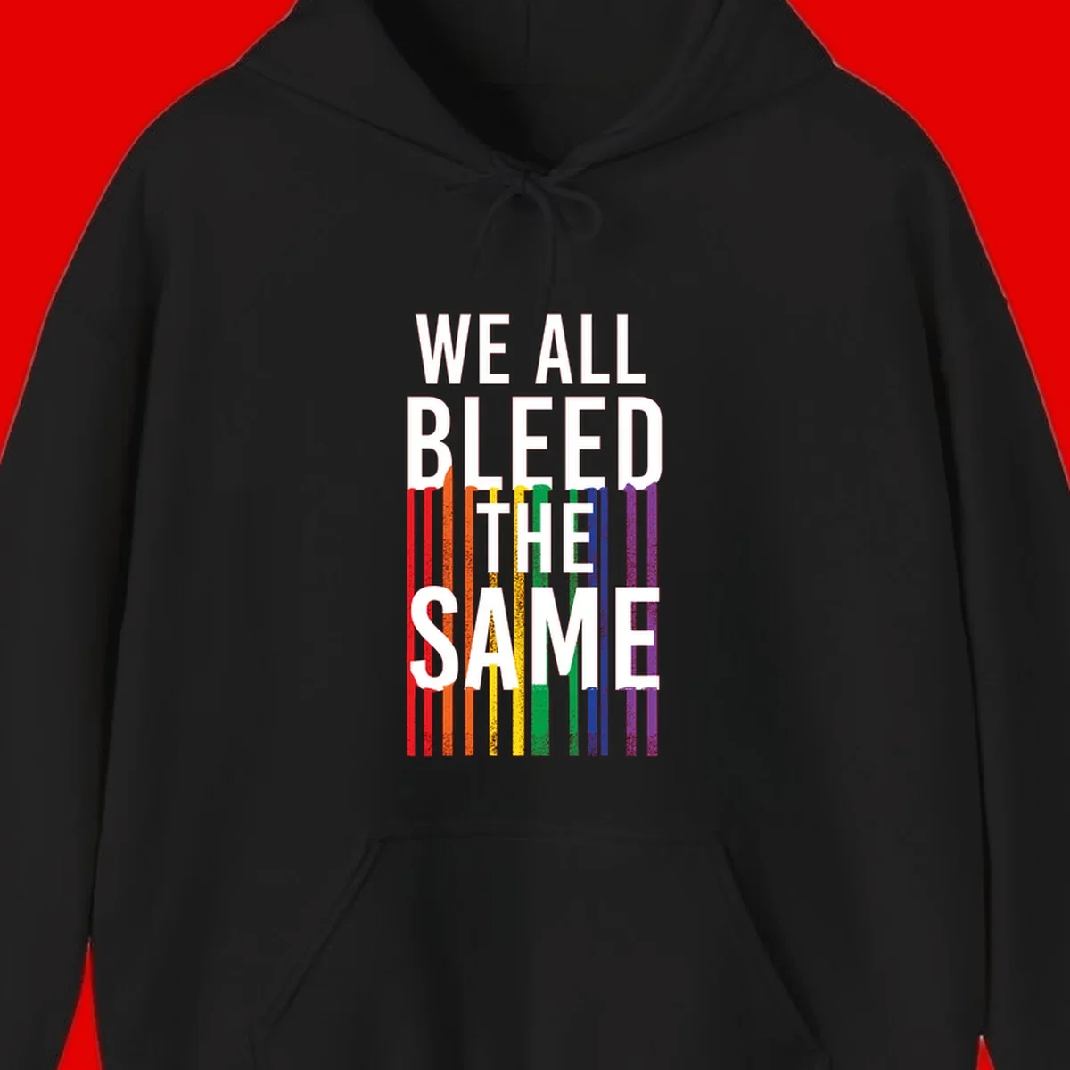 White bold text 'We All Bleed The Same' over rainbow vertical stripes in pride flag colors on gray background
