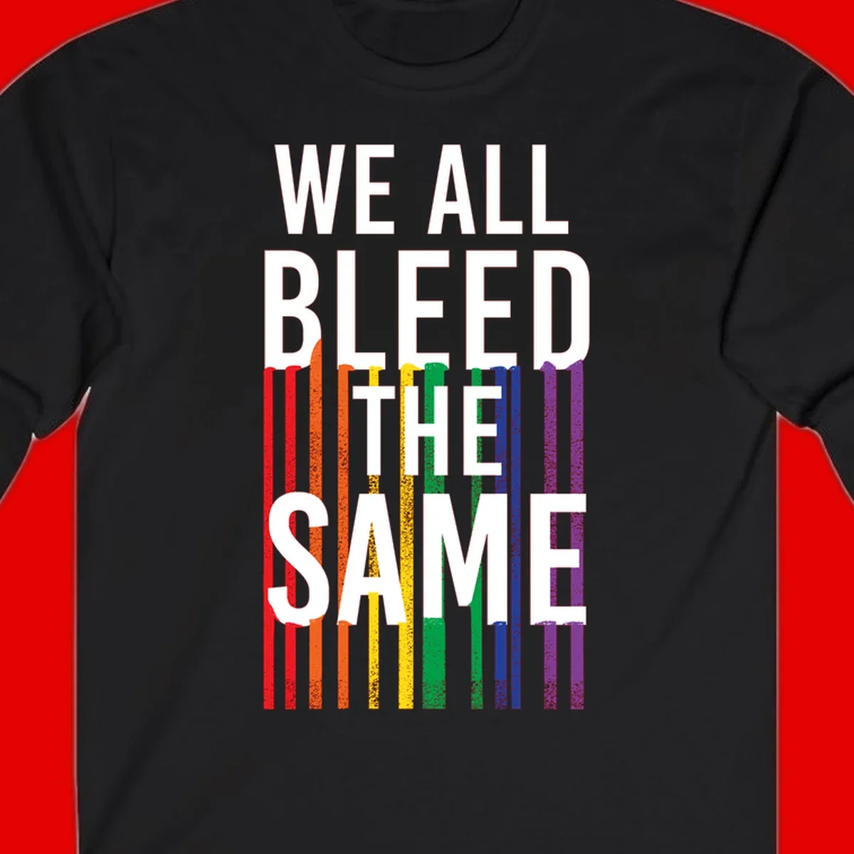 White bold text 'We All Bleed The Same' over rainbow vertical stripes in pride flag colors on gray background