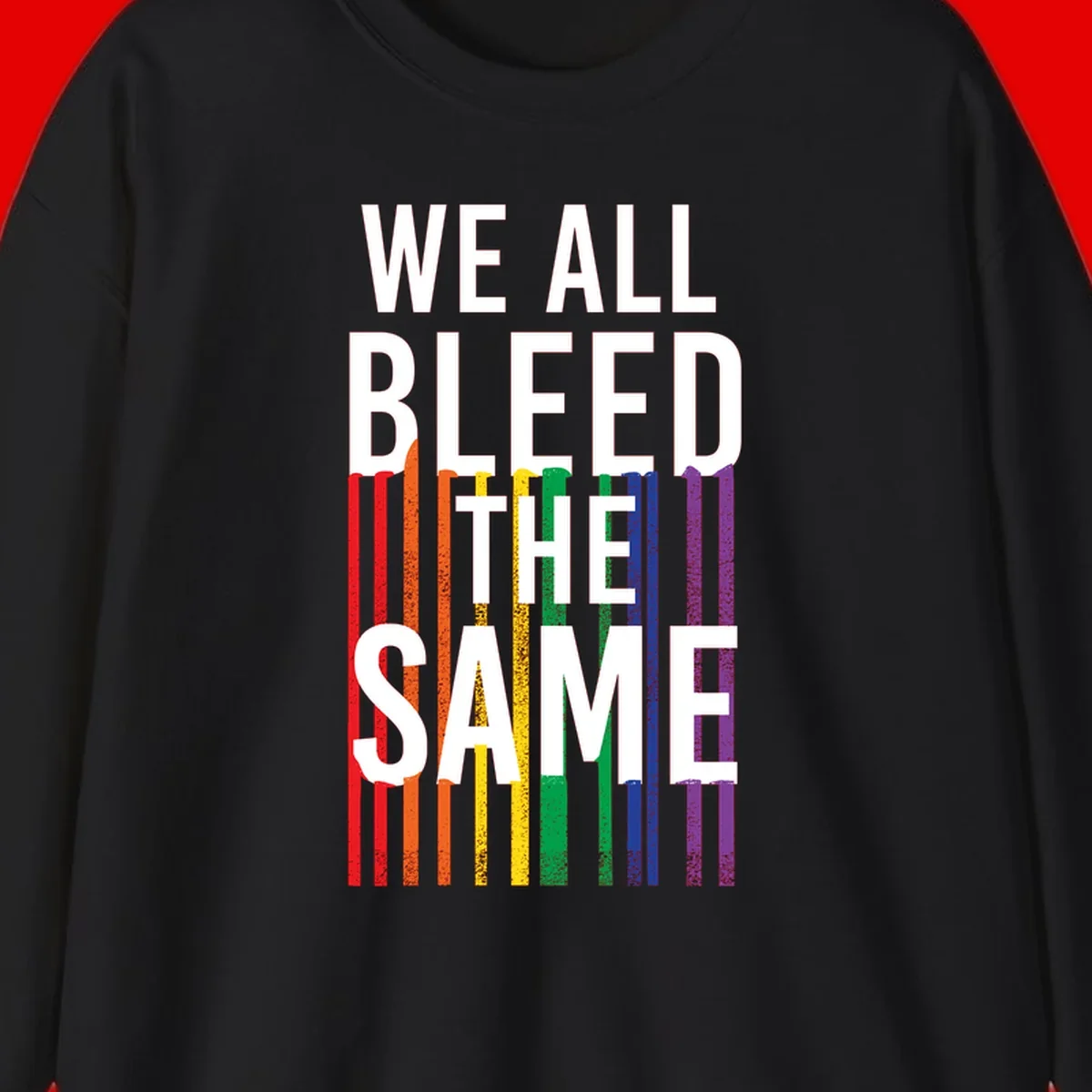 White bold text 'We All Bleed The Same' over rainbow vertical stripes in pride flag colors on gray background