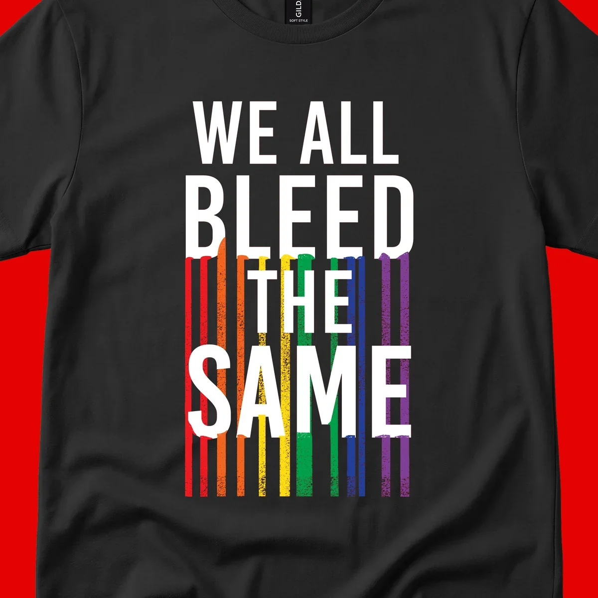 White bold text 'We All Bleed The Same' over rainbow vertical stripes in pride flag colors on gray background