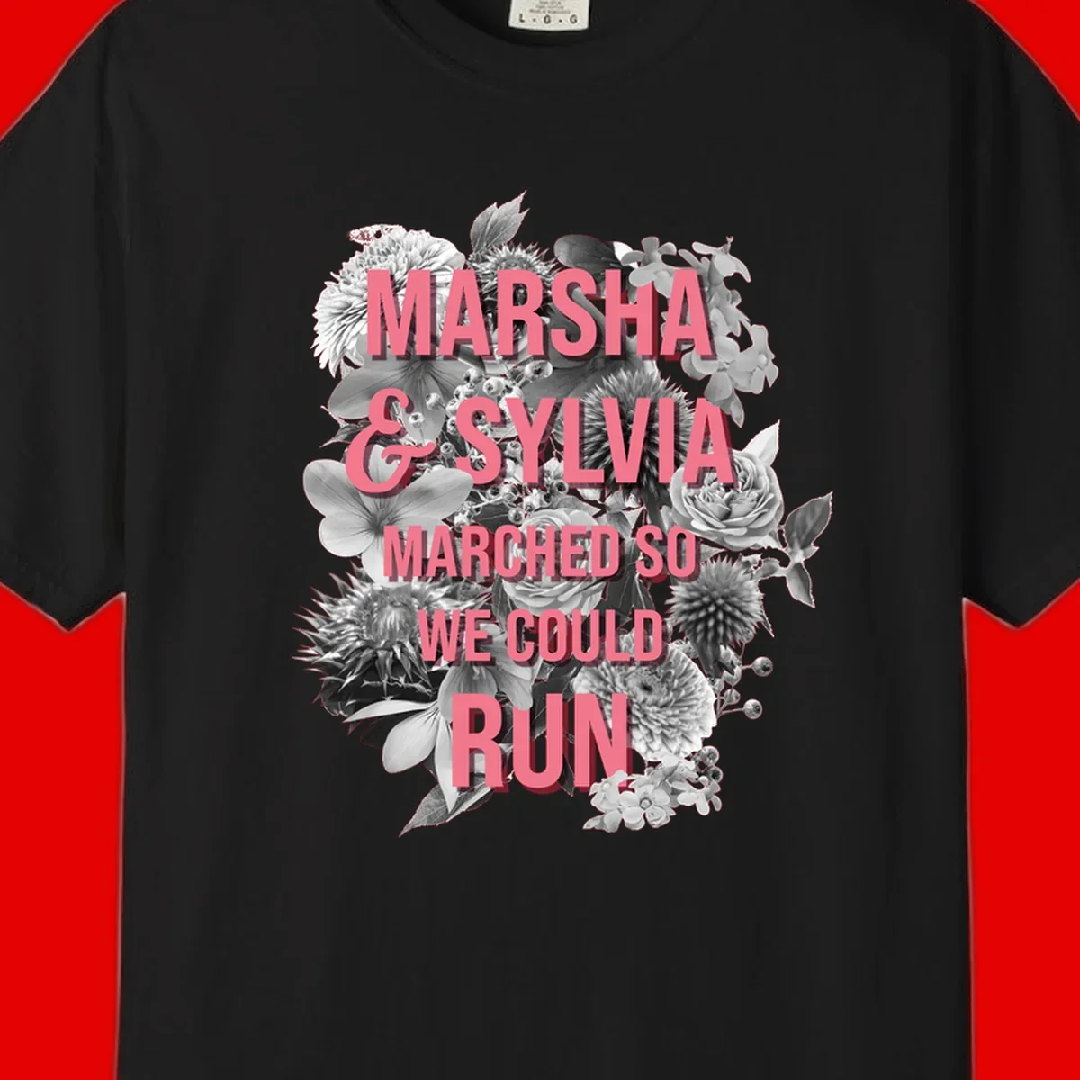 Pink text reading 'Marsha & Sylvia Marched So We Could Run' overlaid on black and white floral arrangement with roses and dahlias