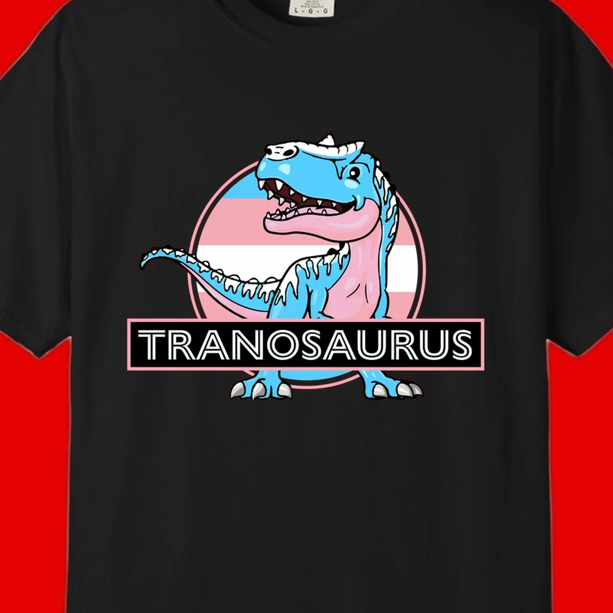 Blue cartoon T-Rex dinosaur with open mouth against pink and white pride flag circular background, labeled Tranosaurus