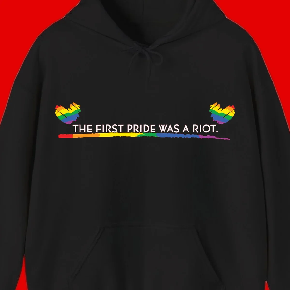 Gray background with white text reading 'THE FIRST PRIDE WAS A RIOT' surrounded by rainbow pride hearts and gradient stripe
