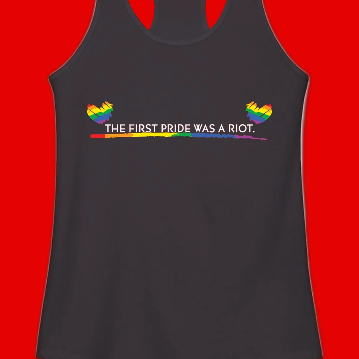 Gray background with white text reading 'THE FIRST PRIDE WAS A RIOT' surrounded by rainbow pride hearts and gradient stripe