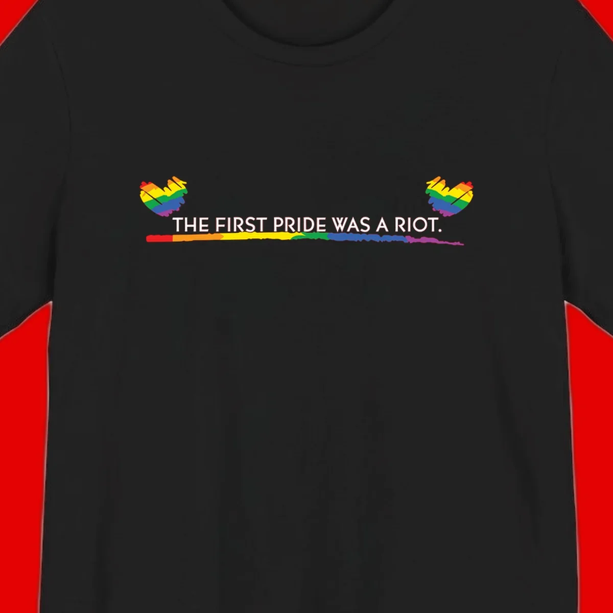 Gray background with white text reading 'THE FIRST PRIDE WAS A RIOT' surrounded by rainbow pride hearts and gradient stripe