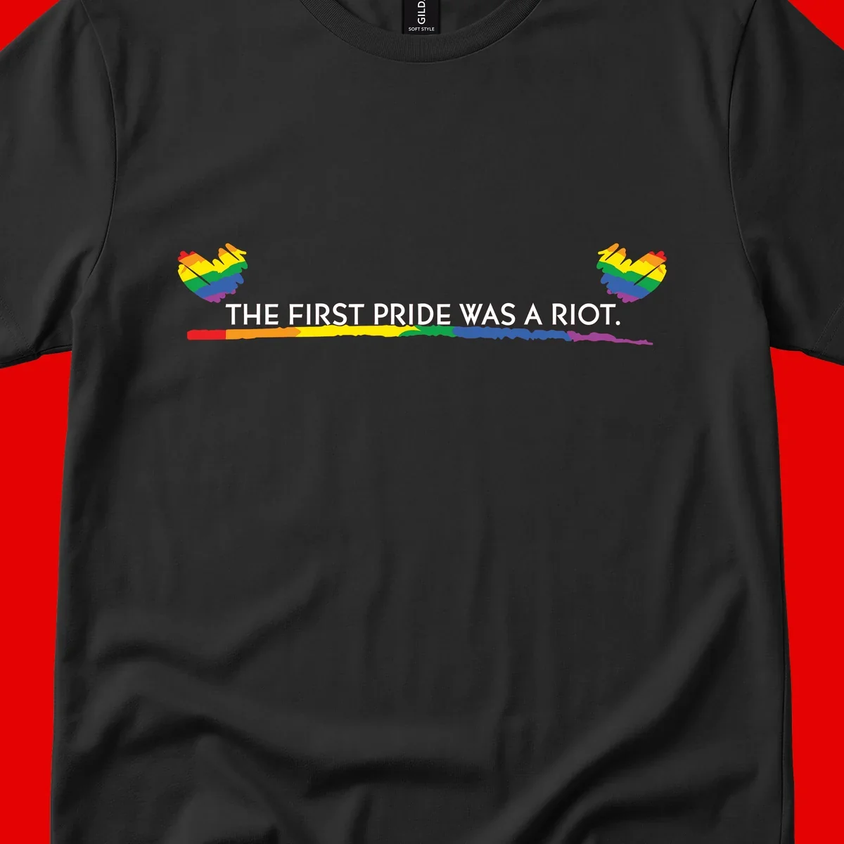 Gray background with white text reading 'THE FIRST PRIDE WAS A RIOT' surrounded by rainbow pride hearts and gradient stripe