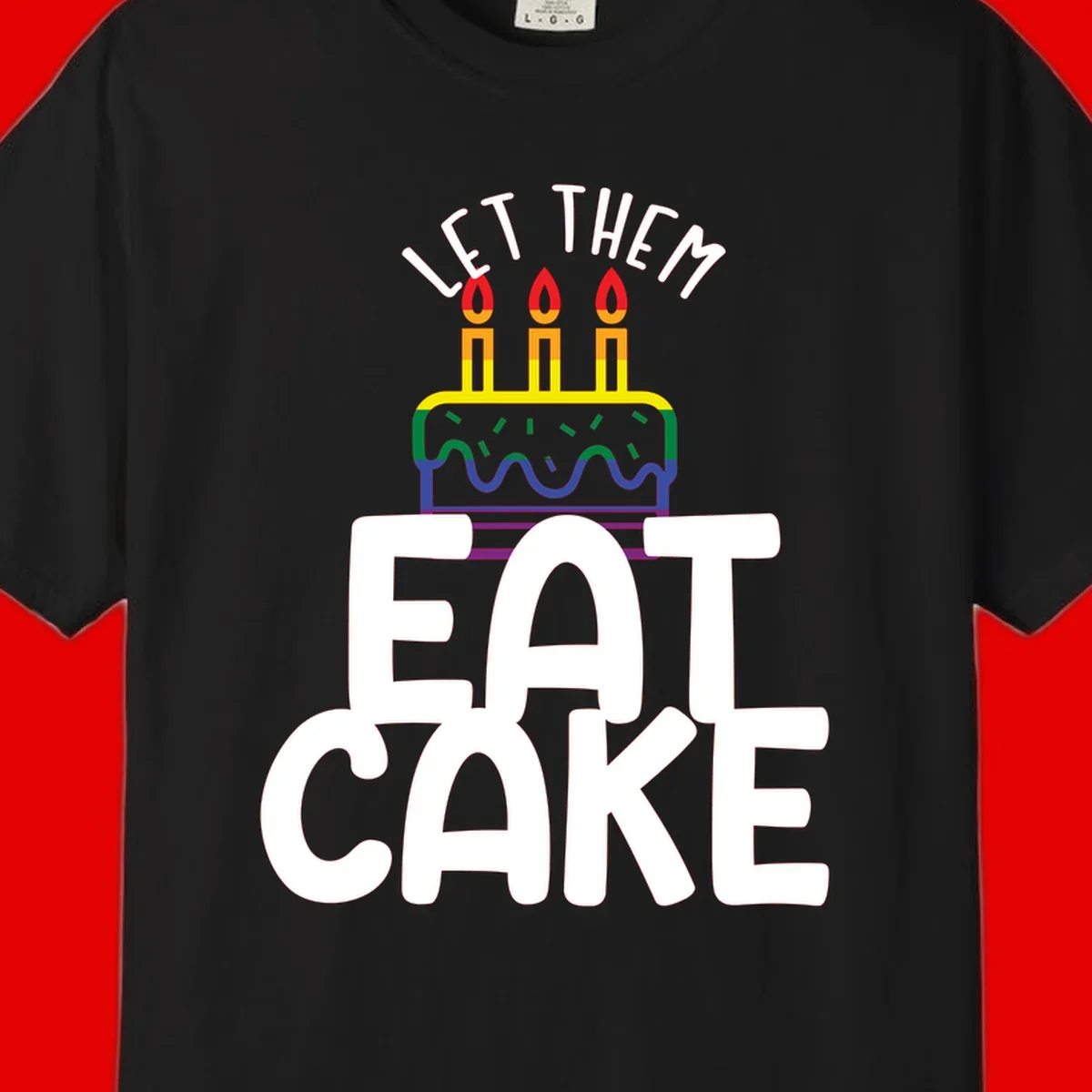 Rainbow-layered birthday cake with three candles above bold white text reading 'Let Them Eat Cake' - a Pride-themed design