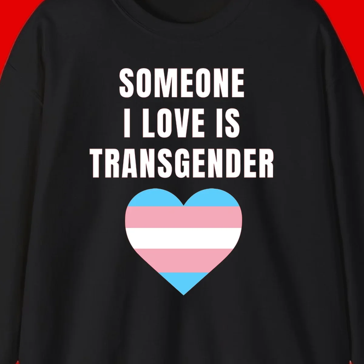 Gray background with white text reading 'Someone I Love Is Transgender' above a heart featuring blue, pink, and white transgender flag stripes