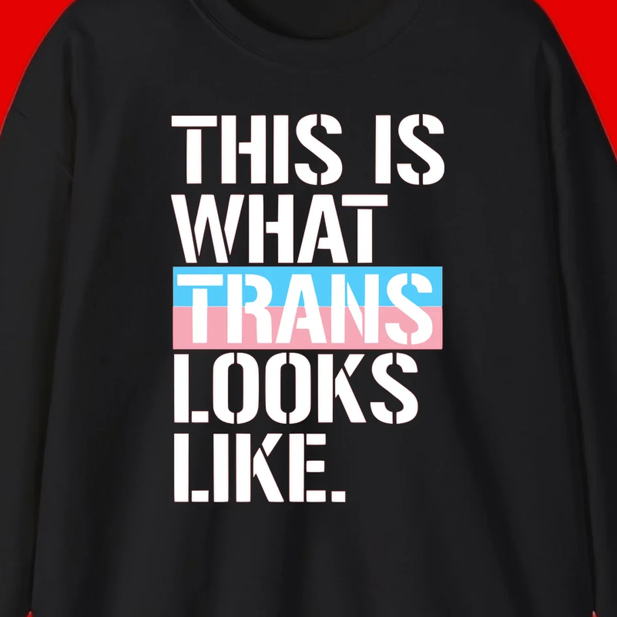Bold typography design reading 'THIS IS WHAT TRANS LOOKS LIKE' with trans pride flag colors in blue and pink stripe