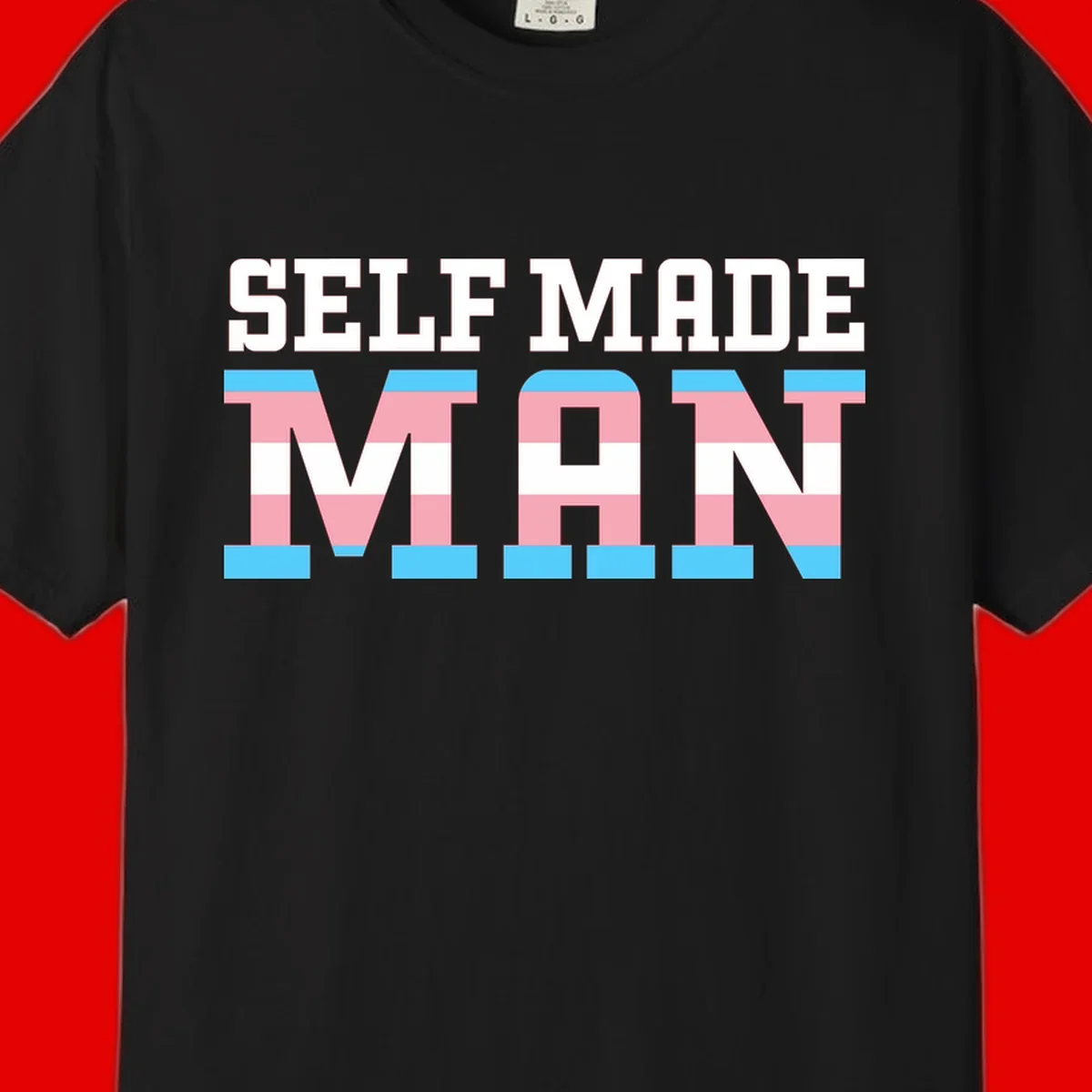 Bold 'Self Made' text filled with transgender pride flag stripes in blue, pink, and white on gray background