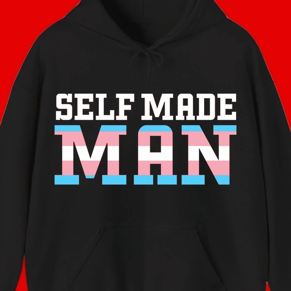Bold 'Self Made' text filled with transgender pride flag stripes in blue, pink, and white on gray background