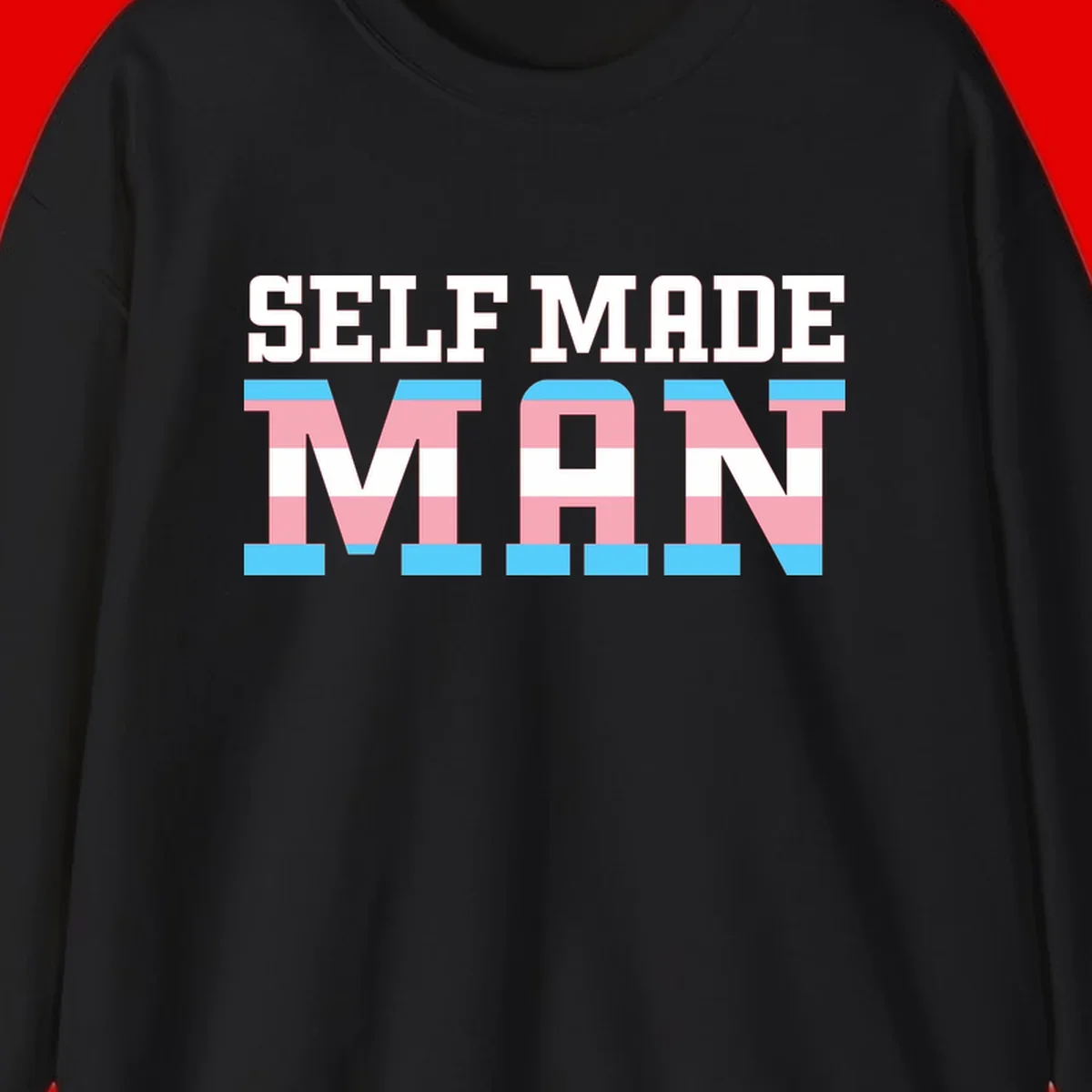 Bold 'Self Made' text filled with transgender pride flag stripes in blue, pink, and white on gray background