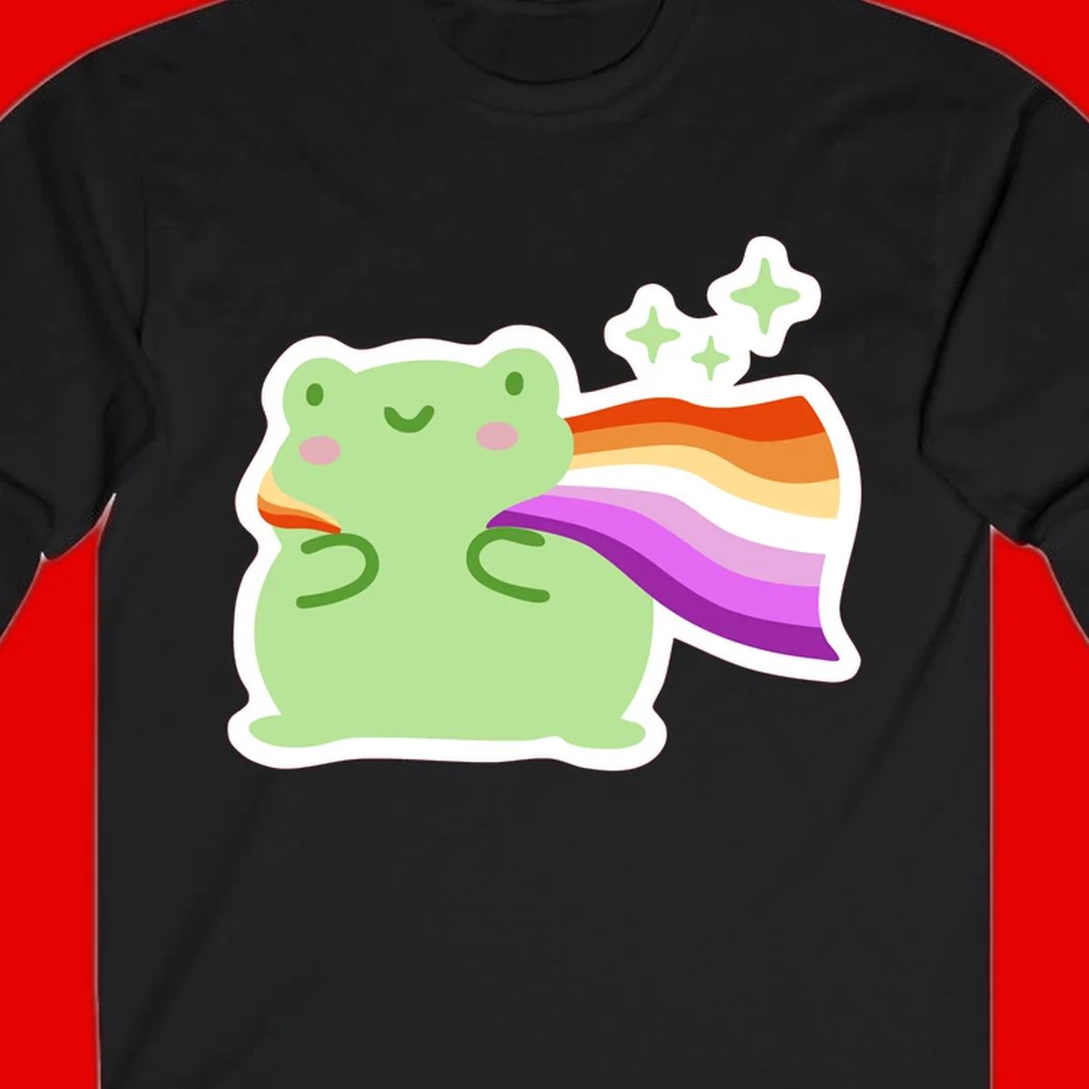 Cute green frog with pink cheeks wearing a rainbow pride cape, surrounded by sparkle stars