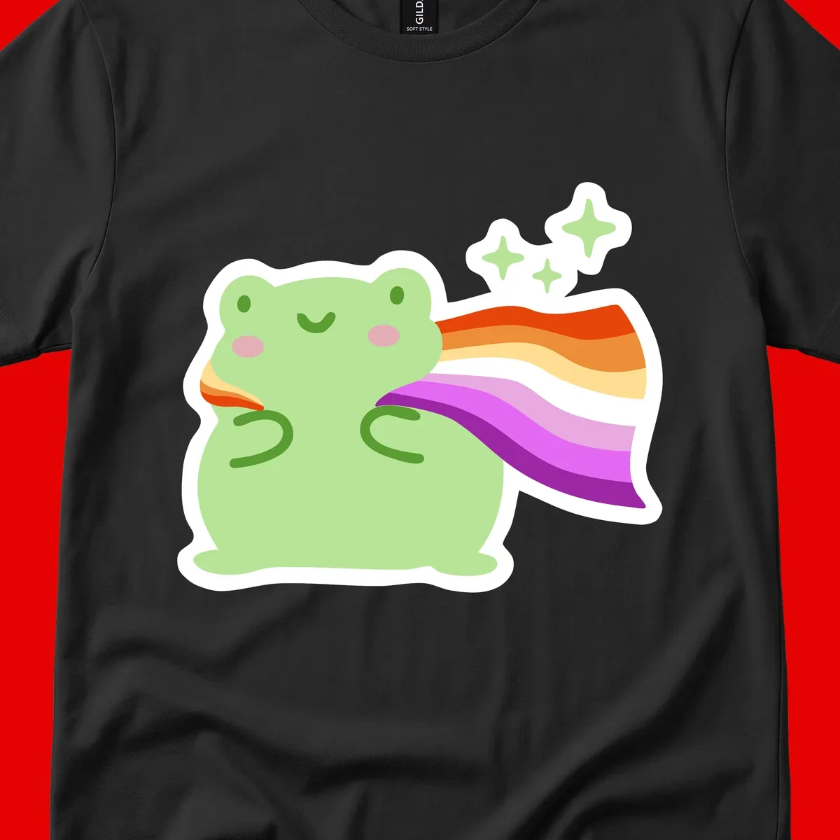 Cute green frog with pink cheeks wearing a rainbow pride cape, surrounded by sparkle stars