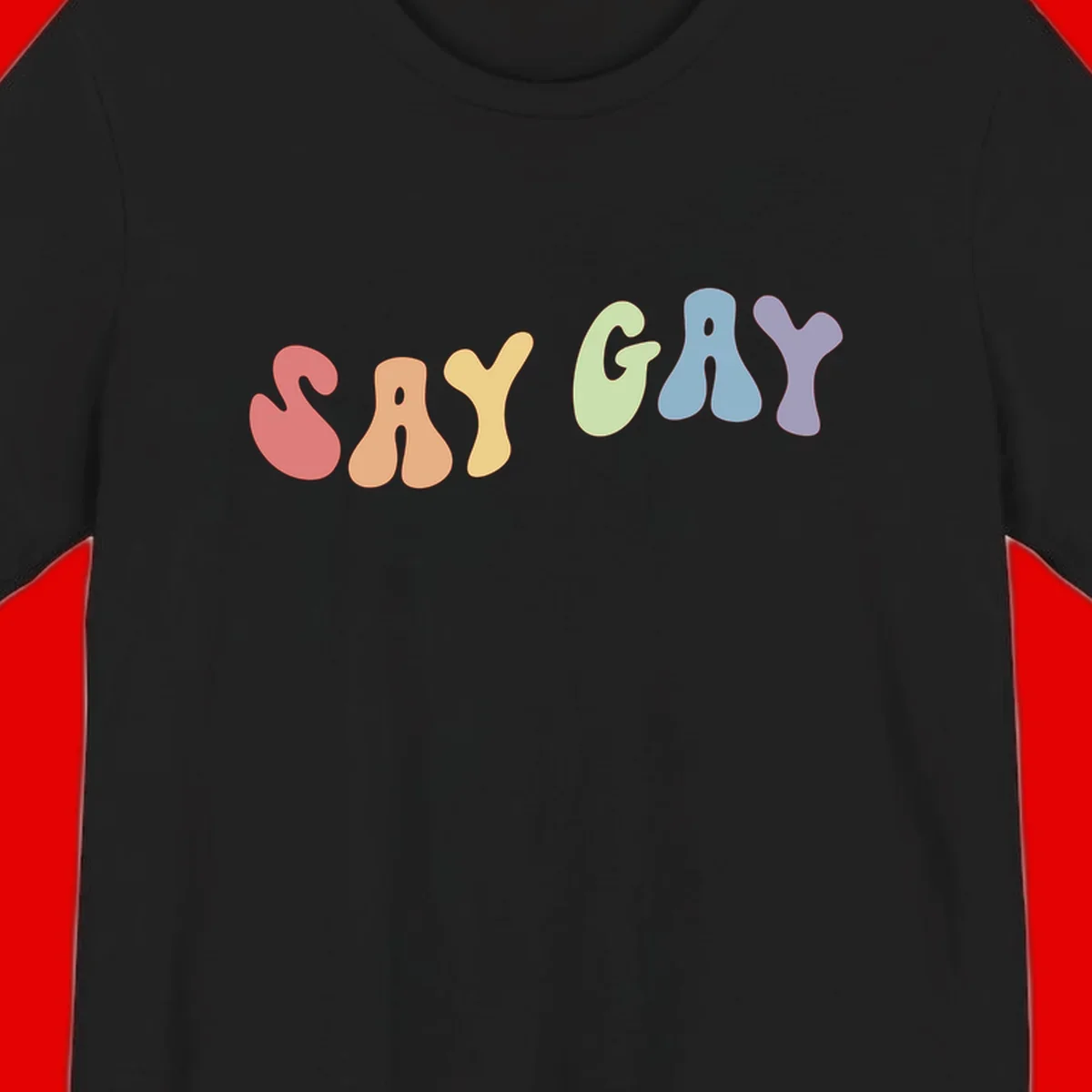 Colorful bubble letters spelling SAY GAY in rainbow pride colors: red, peach, yellow, green, blue, and purple on gray background