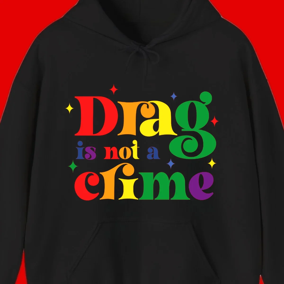Colorful rainbow typography spelling 'Drag is not a crime' with decorative stars on gray background