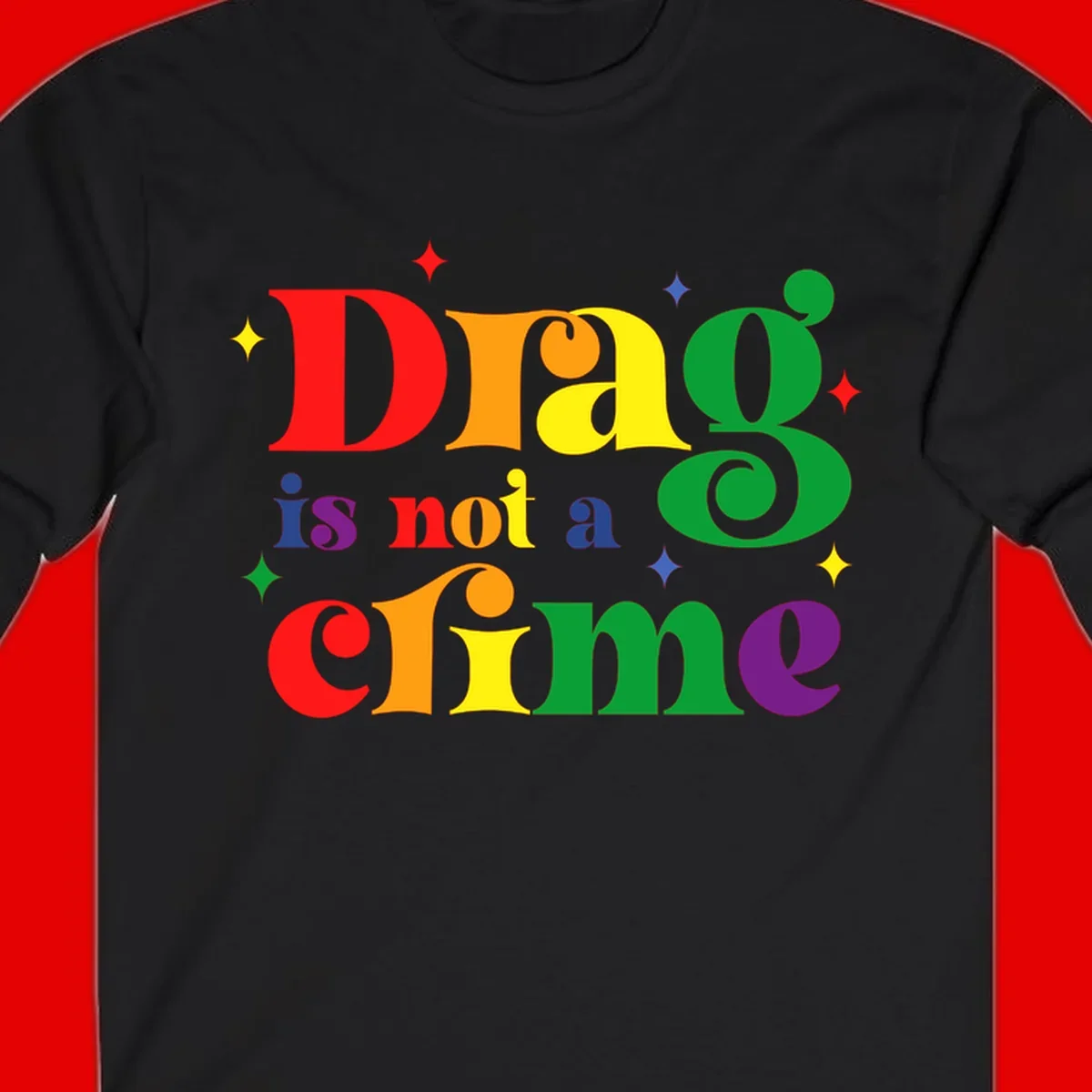 Colorful rainbow typography spelling 'Drag is not a crime' with decorative stars on gray background