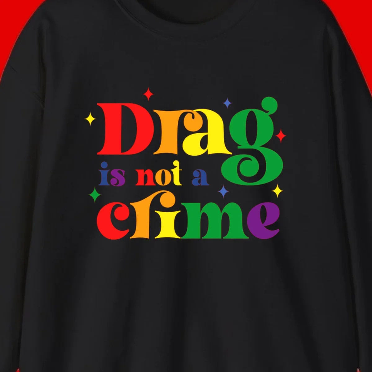 Colorful rainbow typography spelling 'Drag is not a crime' with decorative stars on gray background