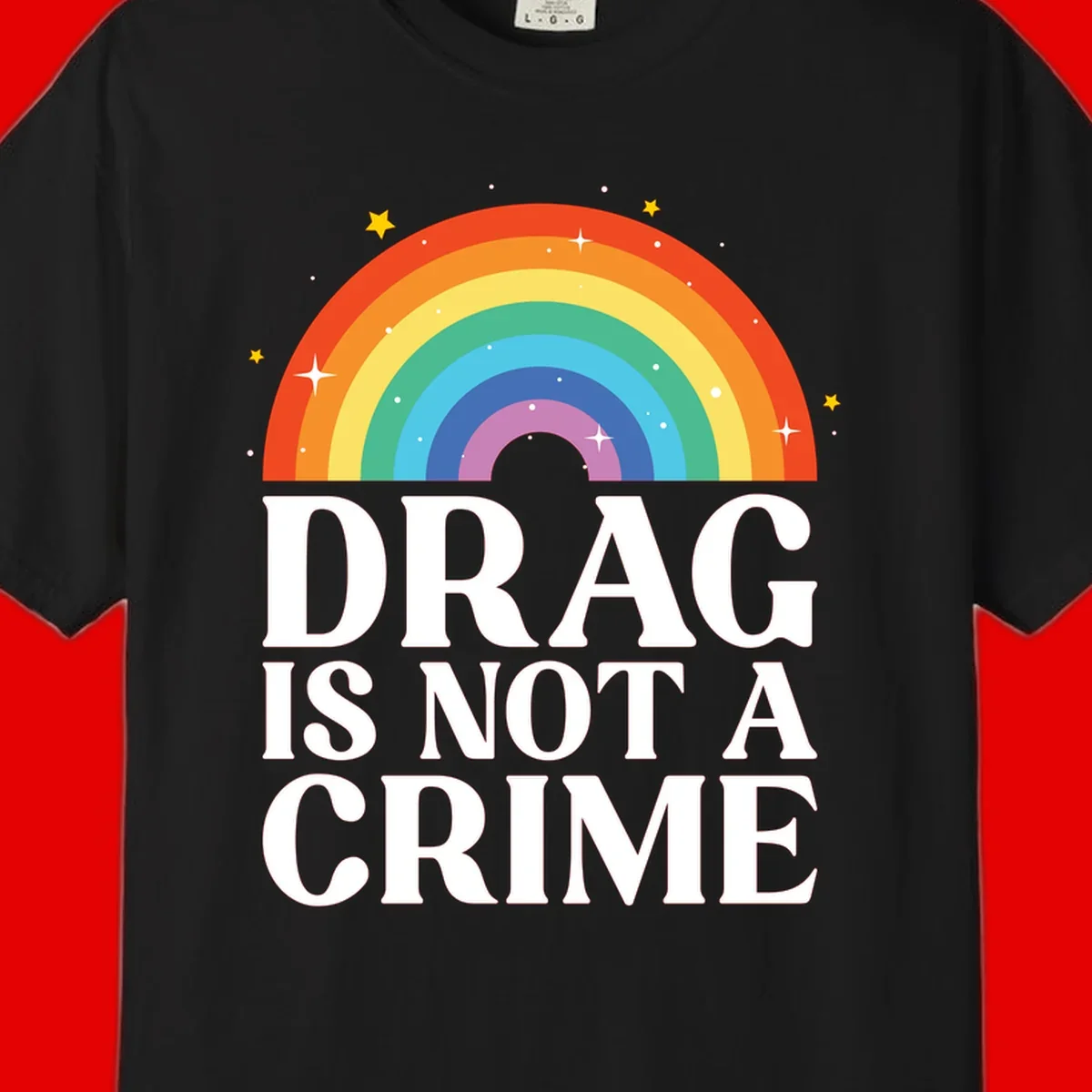 Colorful rainbow arc with stars above white text reading 'Drag Is Not A Crime' on gray background