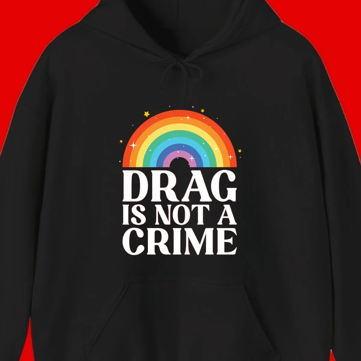 Colorful rainbow arc with stars above white text reading 'Drag Is Not A Crime' on gray background