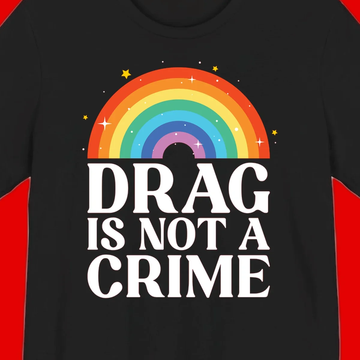 Colorful rainbow arc with stars above white text reading 'Drag Is Not A Crime' on gray background
