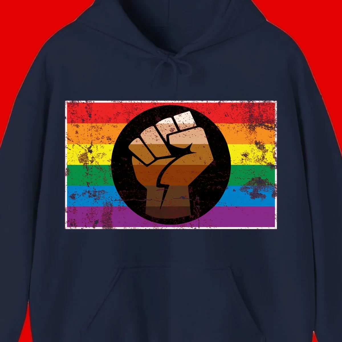 Distressed circular badge featuring a raised brown fist overlaid on a rainbow pride flag background, symbolizing LGBTQ+ solidarity and empowerment