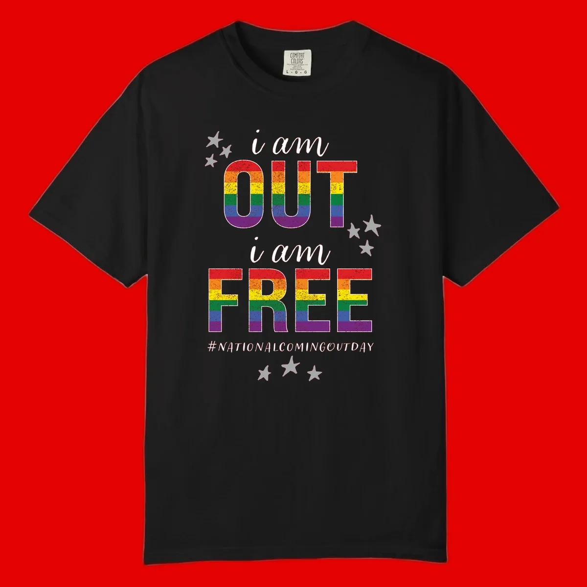 Rainbow-striped letters spelling 'i am OUT i am FREE' with decorative stars on gray background celebrating National Coming Out Day pride.