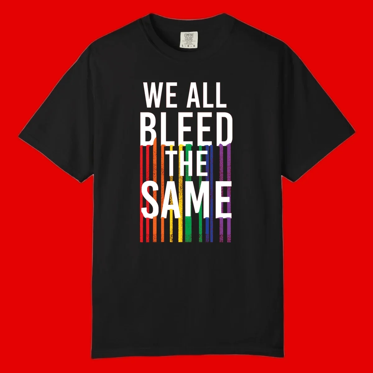 White bold text 'We All Bleed The Same' over rainbow vertical stripes in pride flag colors on gray background