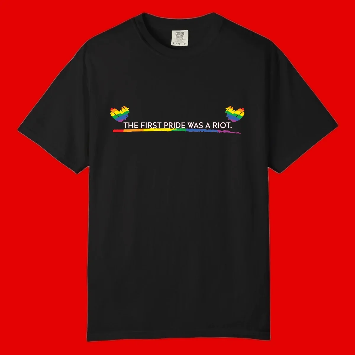 Gray background with white text reading 'THE FIRST PRIDE WAS A RIOT' surrounded by rainbow pride hearts and gradient stripe