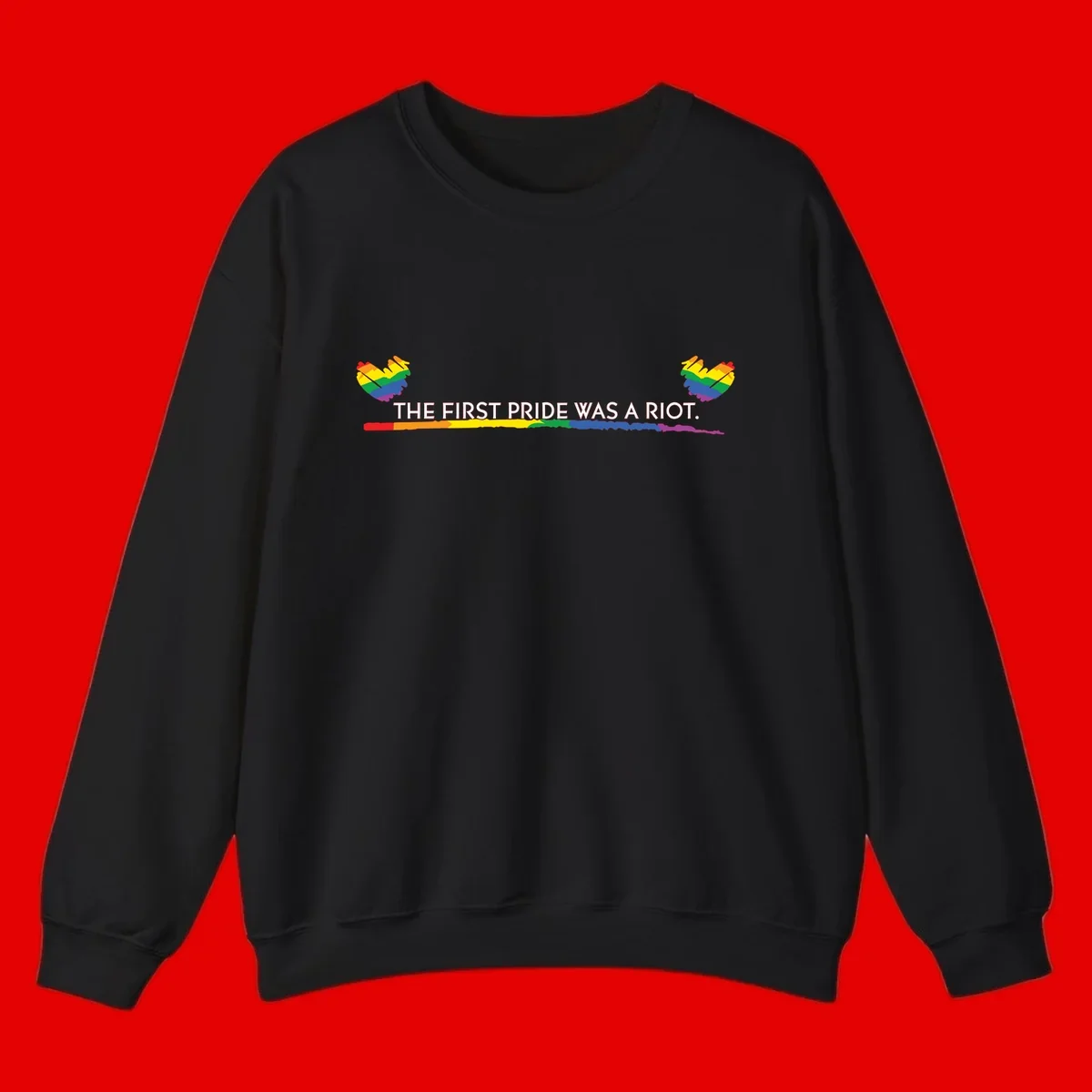 Gray background with white text reading 'THE FIRST PRIDE WAS A RIOT' surrounded by rainbow pride hearts and gradient stripe