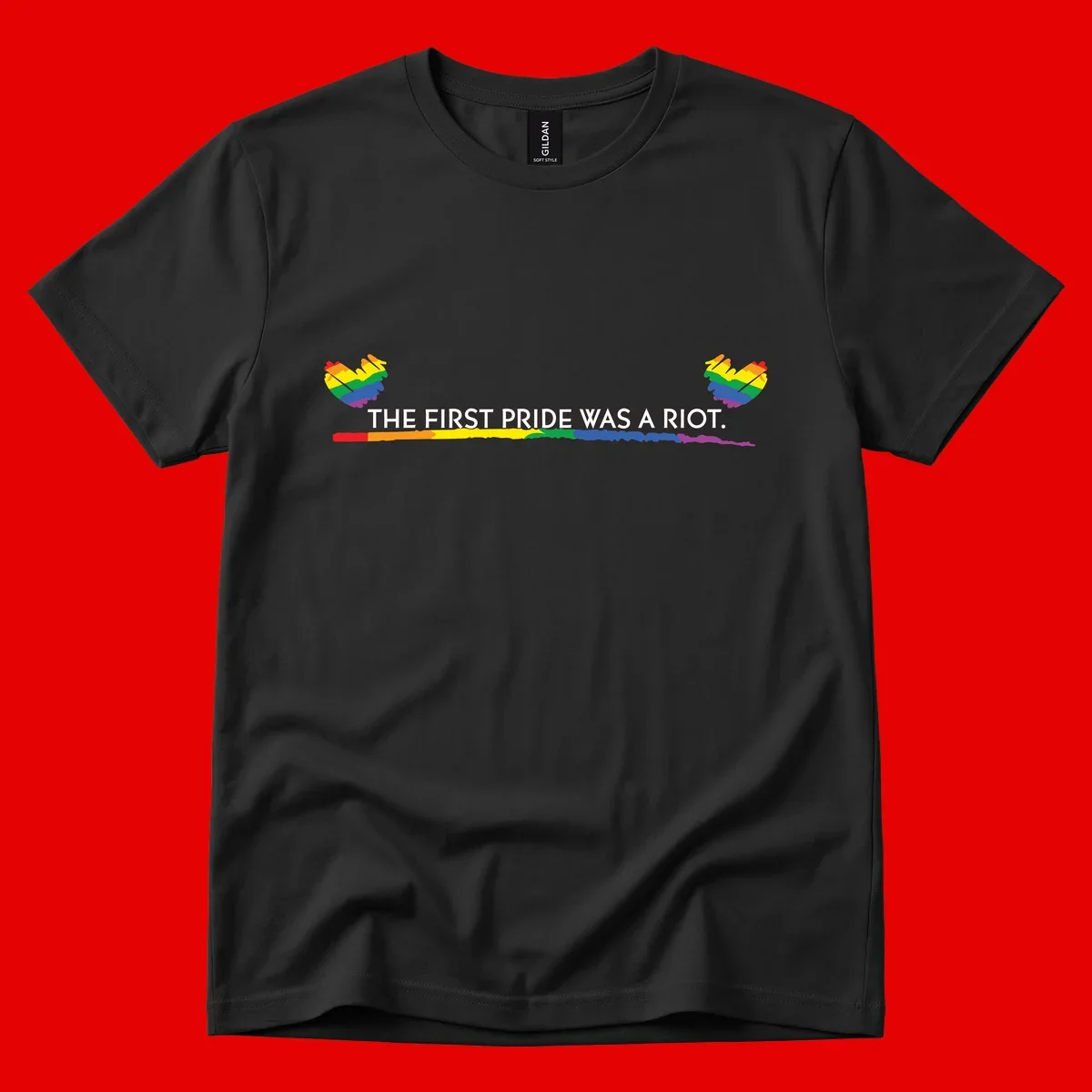 Gray background with white text reading 'THE FIRST PRIDE WAS A RIOT' surrounded by rainbow pride hearts and gradient stripe