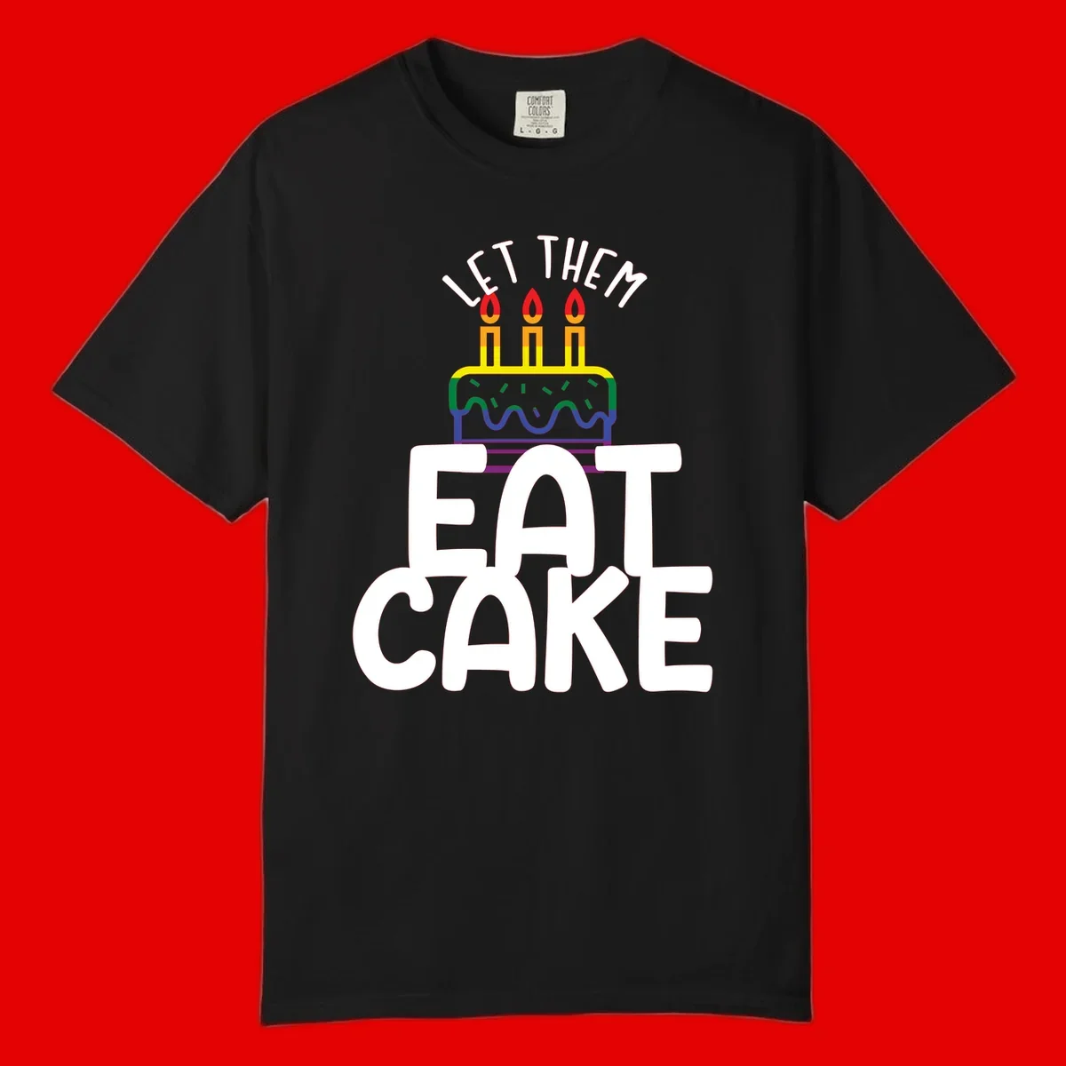 Rainbow-layered birthday cake with three candles above bold white text reading 'Let Them Eat Cake' - a Pride-themed design
