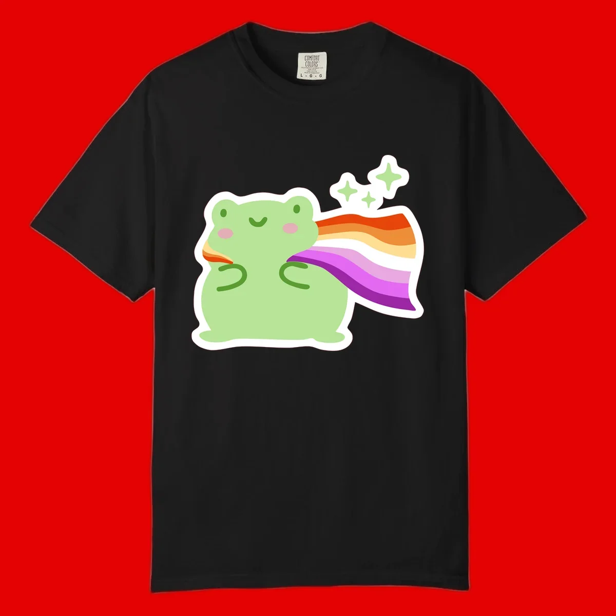 Cute green frog with pink cheeks wearing a rainbow pride cape, surrounded by sparkle stars