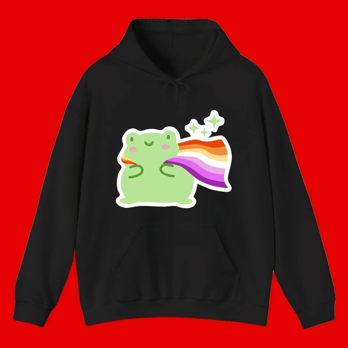 Cute green frog with pink cheeks wearing a rainbow pride cape, surrounded by sparkle stars