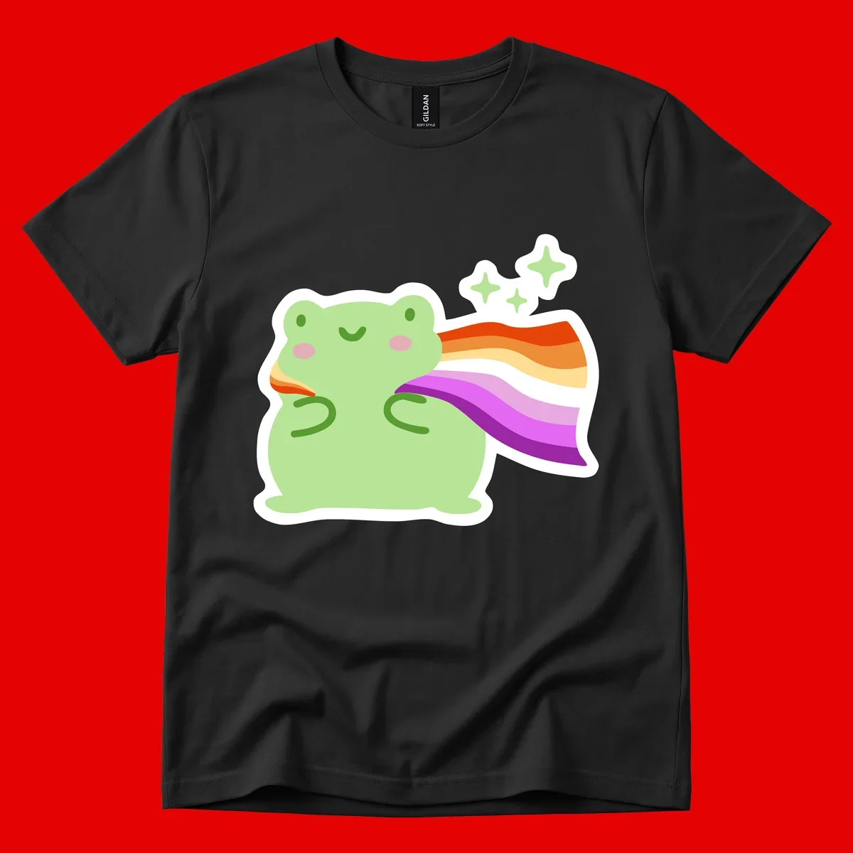 Cute green frog with pink cheeks wearing a rainbow pride cape, surrounded by sparkle stars