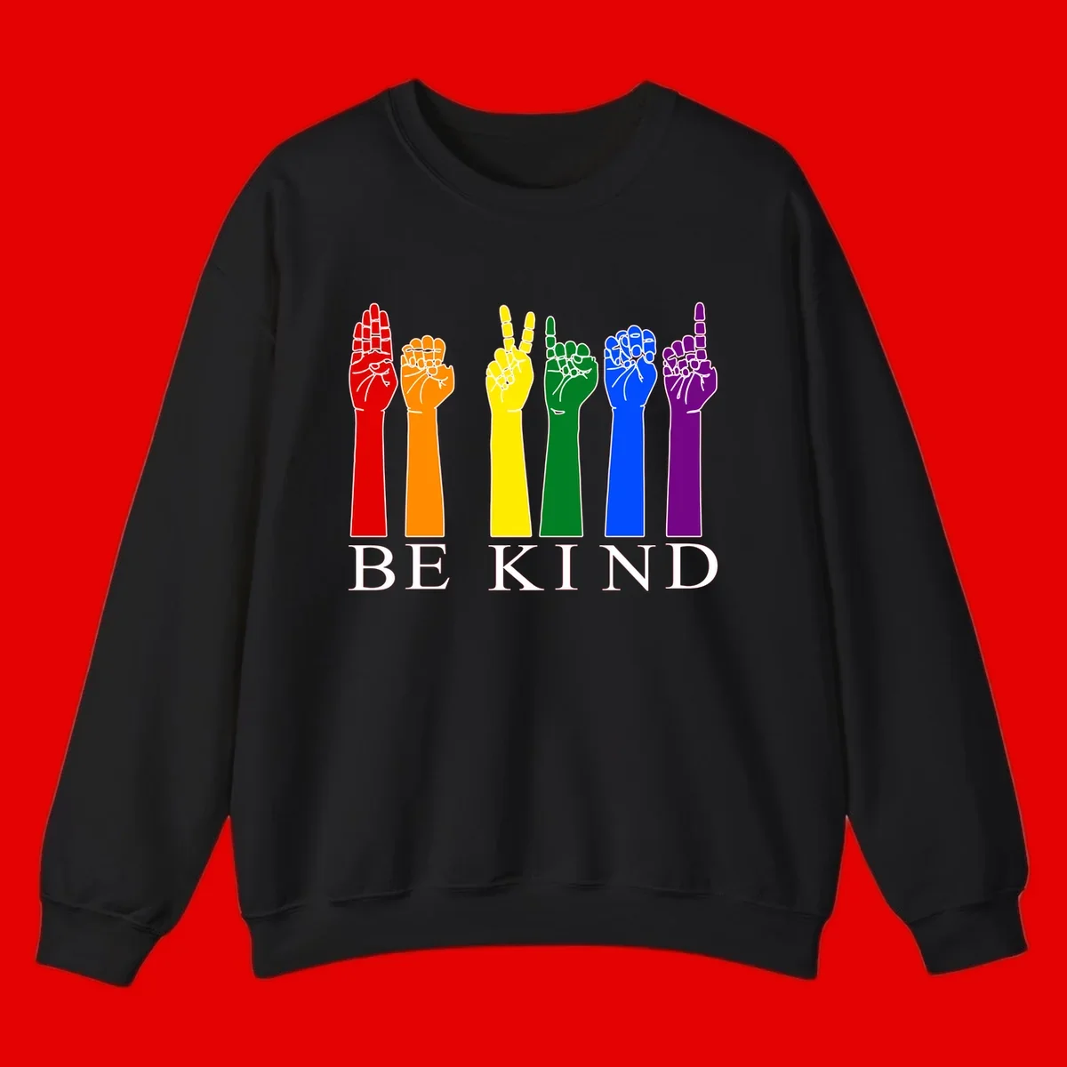 Six rainbow-colored raised hands in red, orange, yellow, green, blue, and purple with white line details and 'BE KIND' text below