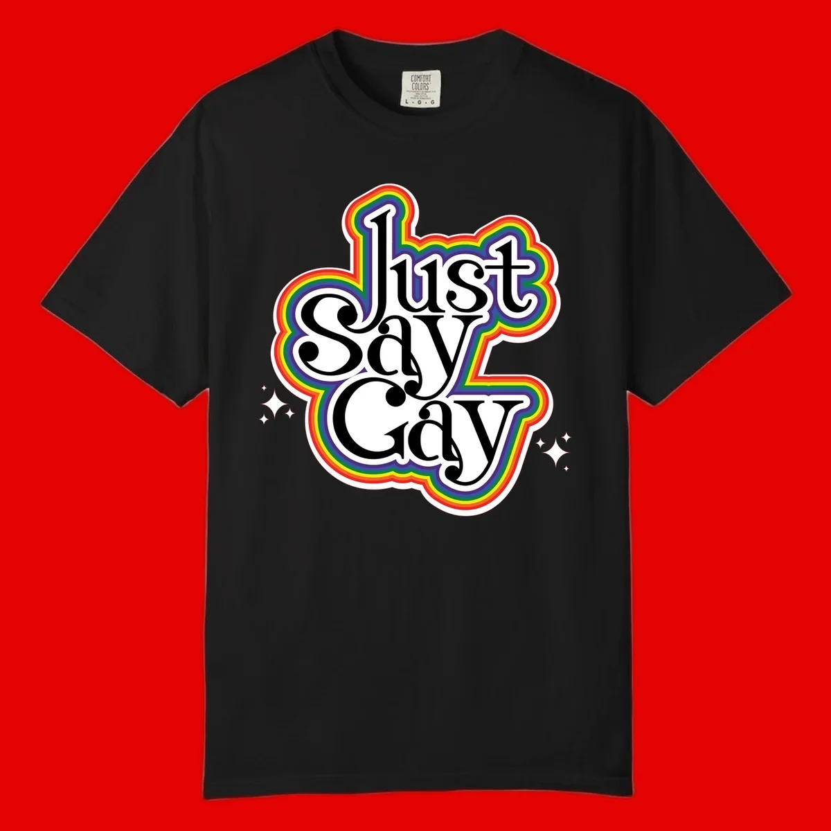 Just Say Gay Pride design with bold black text surrounded by vibrant rainbow border and sparkle accents on gray background