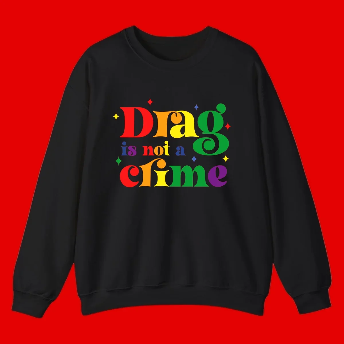 Colorful rainbow typography spelling 'Drag is not a crime' with decorative stars on gray background