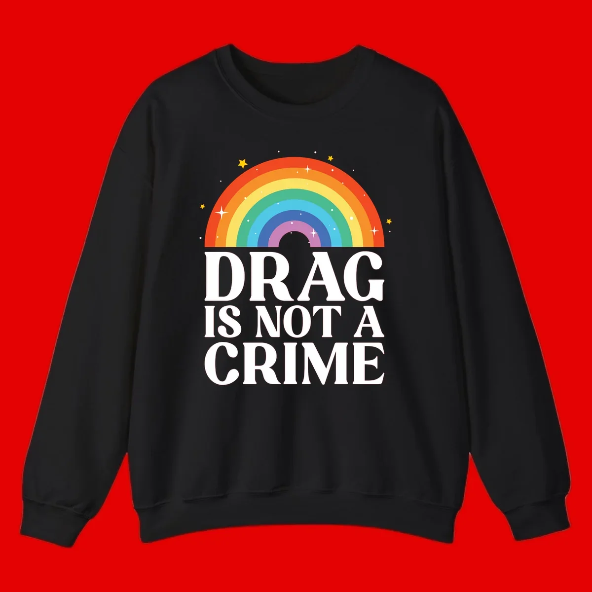 Colorful rainbow arc with stars above white text reading 'Drag Is Not A Crime' on gray background