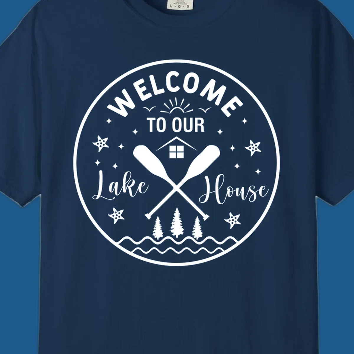 Welcome to our lake house circular design with oars, house, trees, and text.
