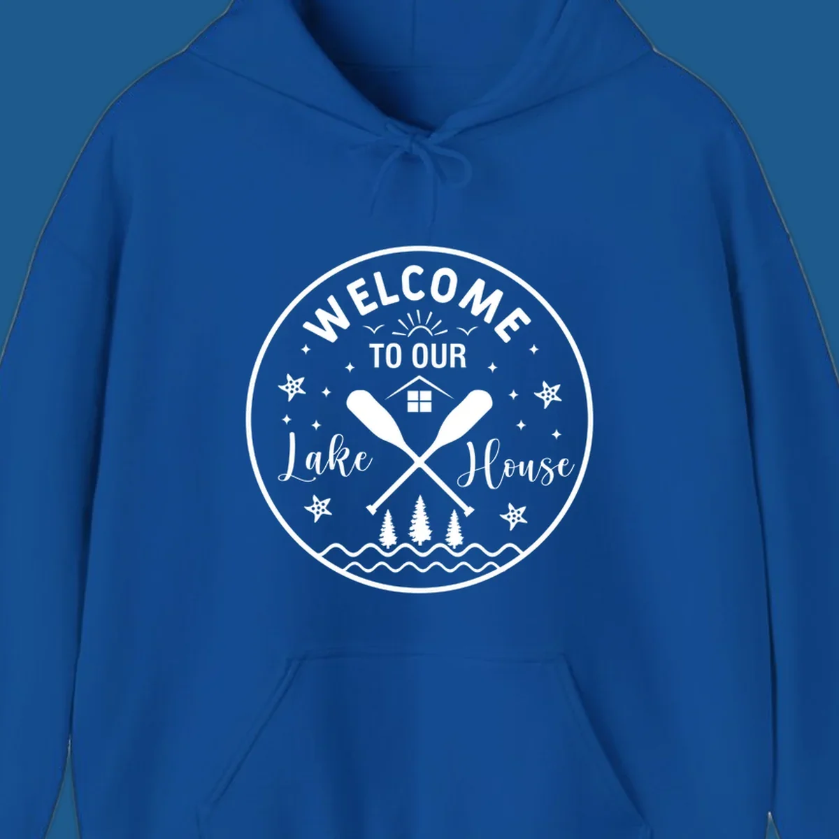 Welcome to our lake house circular design with oars, house, trees, and text.