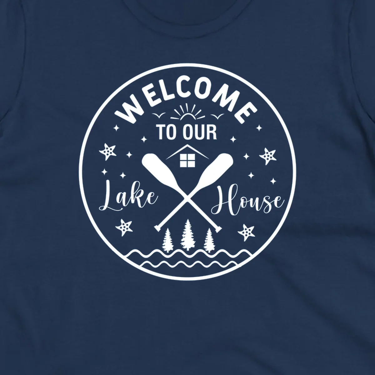 Welcome to our lake house circular design with oars, house, trees, and text.