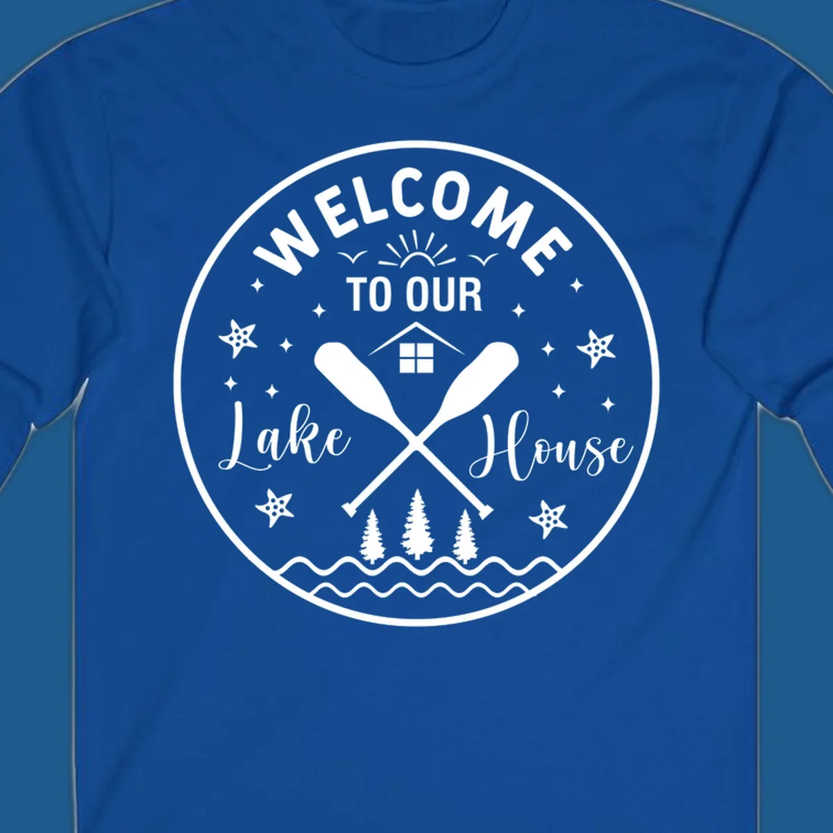 Welcome to our lake house circular design with oars, house, trees, and text.