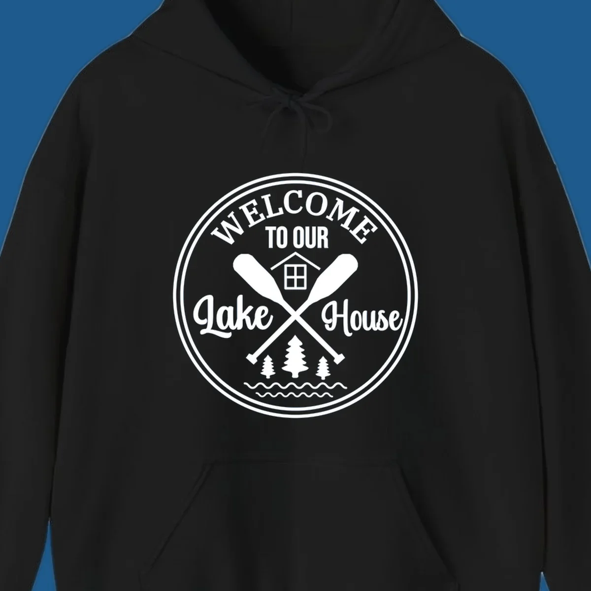 Circular badge design with text 'WELCOME TO OUR Lake House', crossed oars, house, trees, and waves.