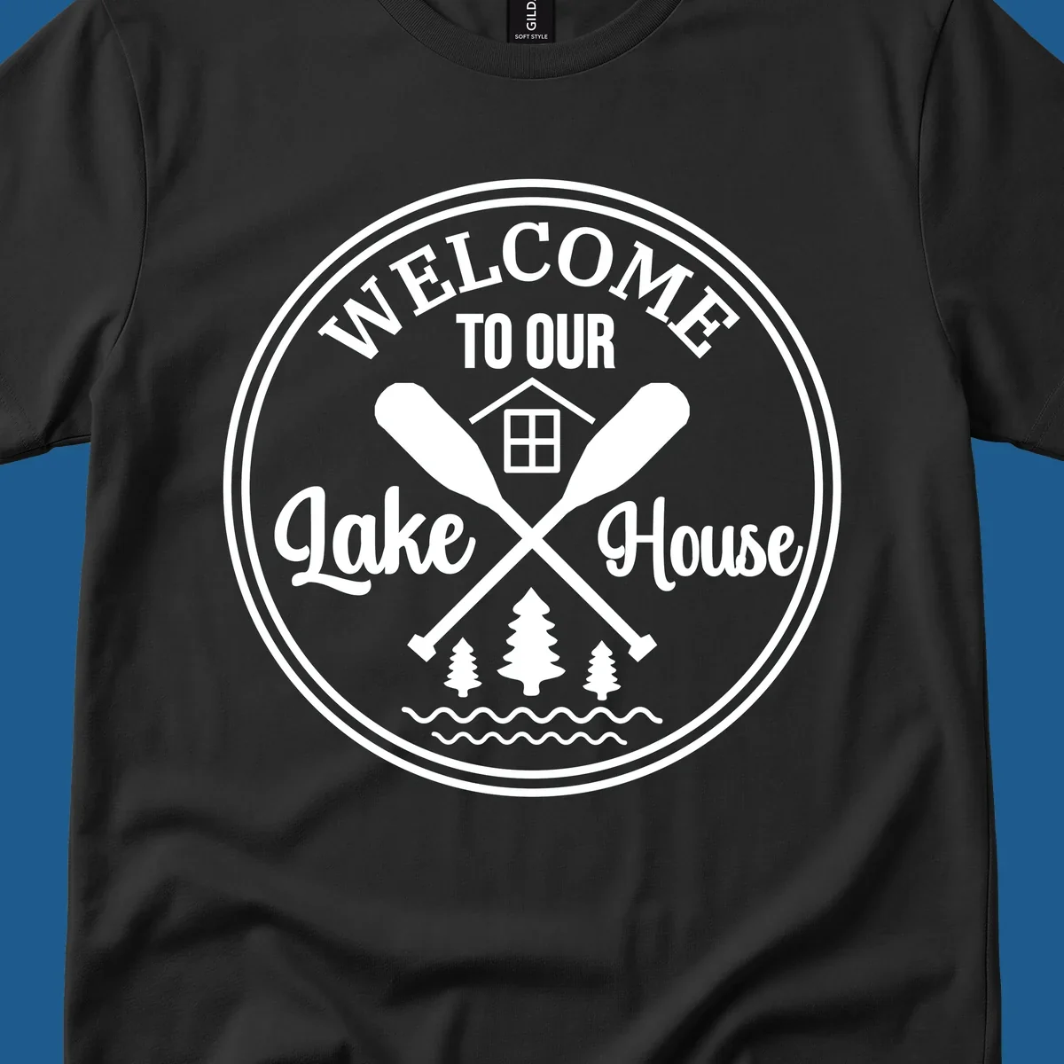 Circular badge design with text 'WELCOME TO OUR Lake House', crossed oars, house, trees, and waves.