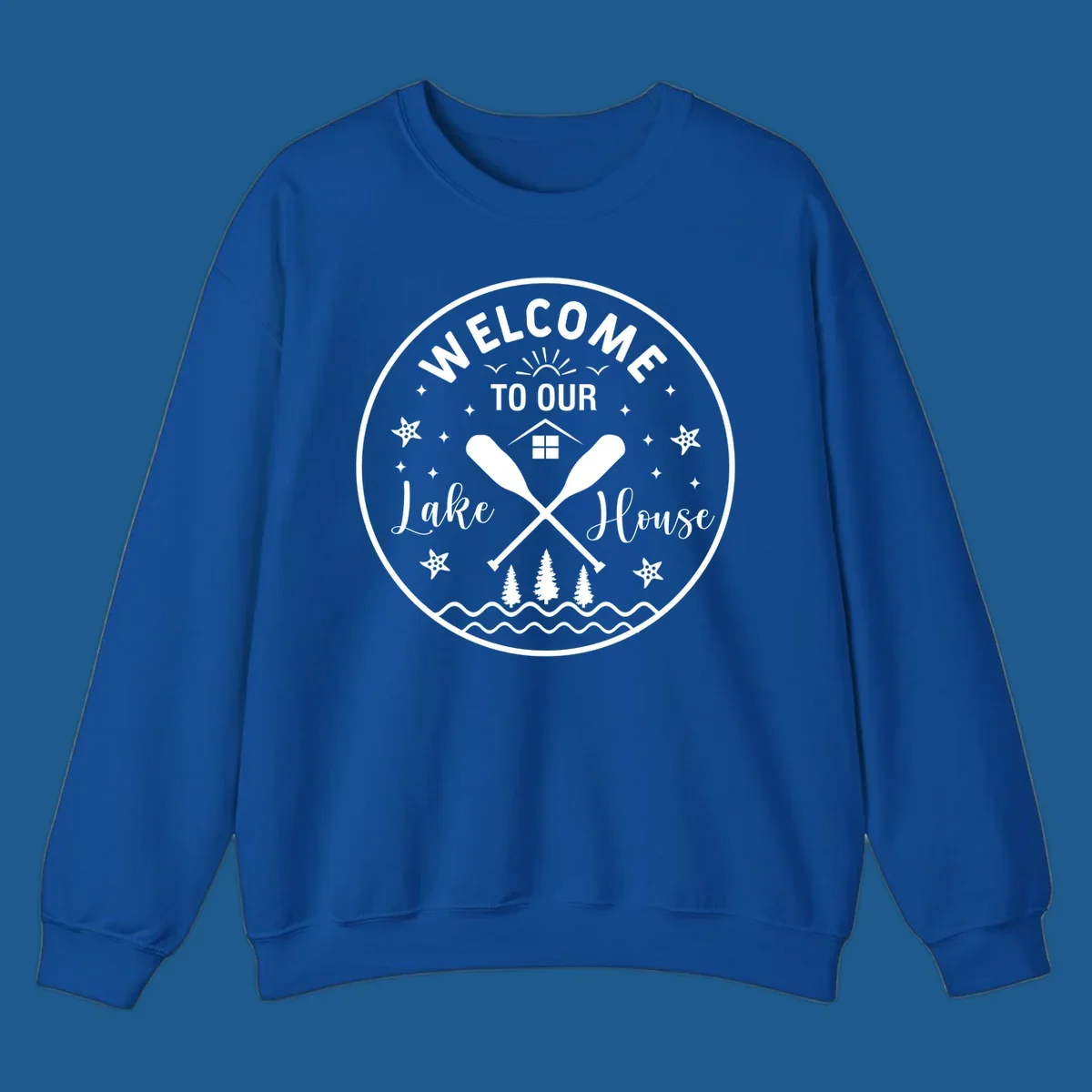 Welcome to our lake house circular design with oars, house, trees, and text.